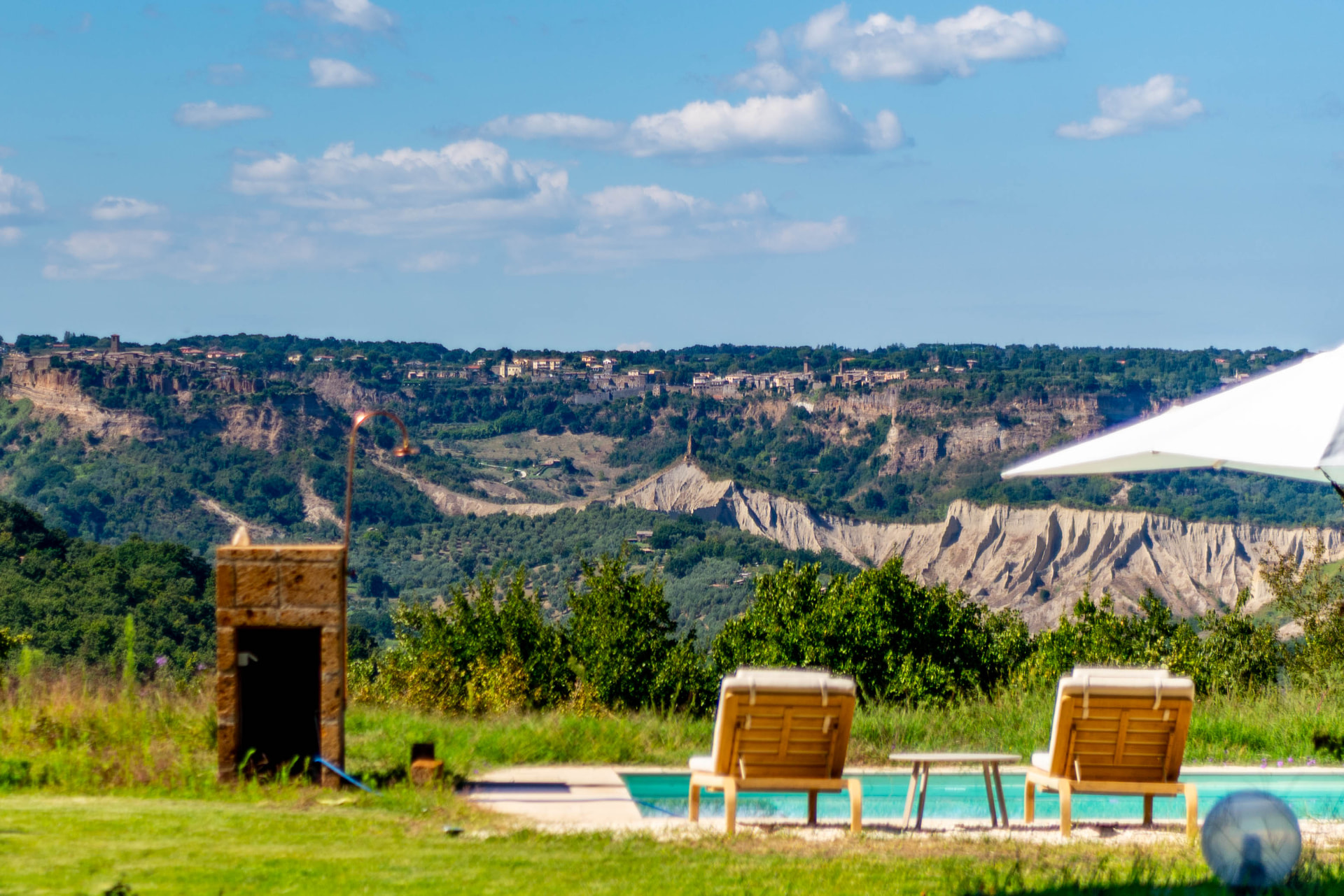 Pool, sunbeds and the calanchi with the hilltop town in the distance