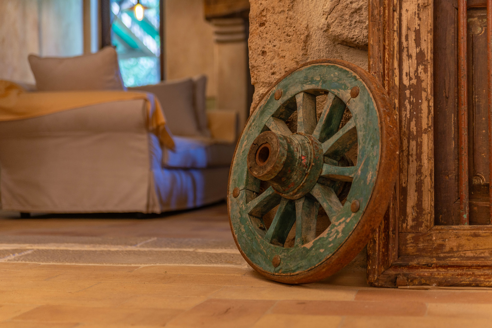 An old green cart wheel beside a wooden doorway