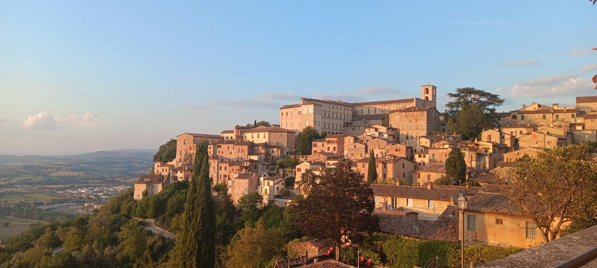 A stone hill town glowing in the golden hour, the valley fading below