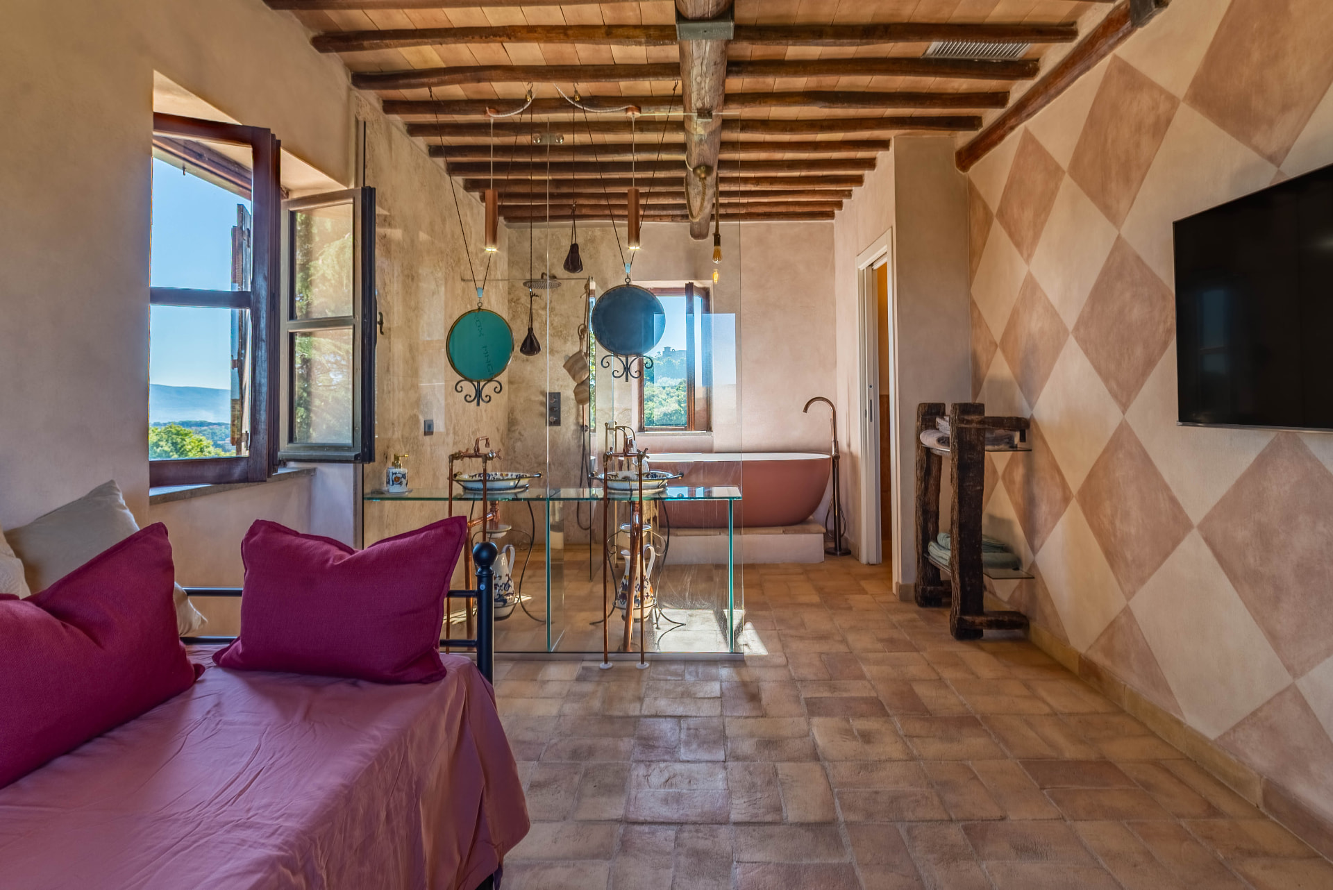 The Quercia bedroom: wide vault of beams, iron bed and windows on the valley
