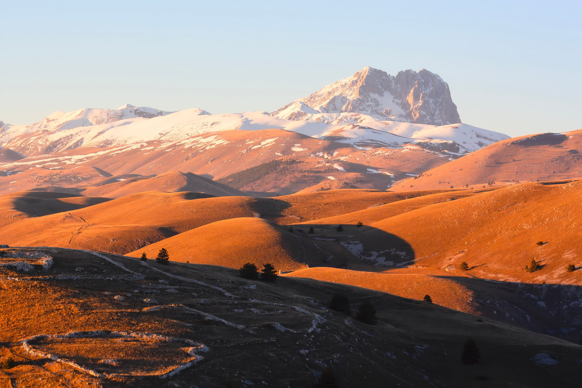 Golden evening light over the high plateau of Campo Imperatore, snow on the peaks