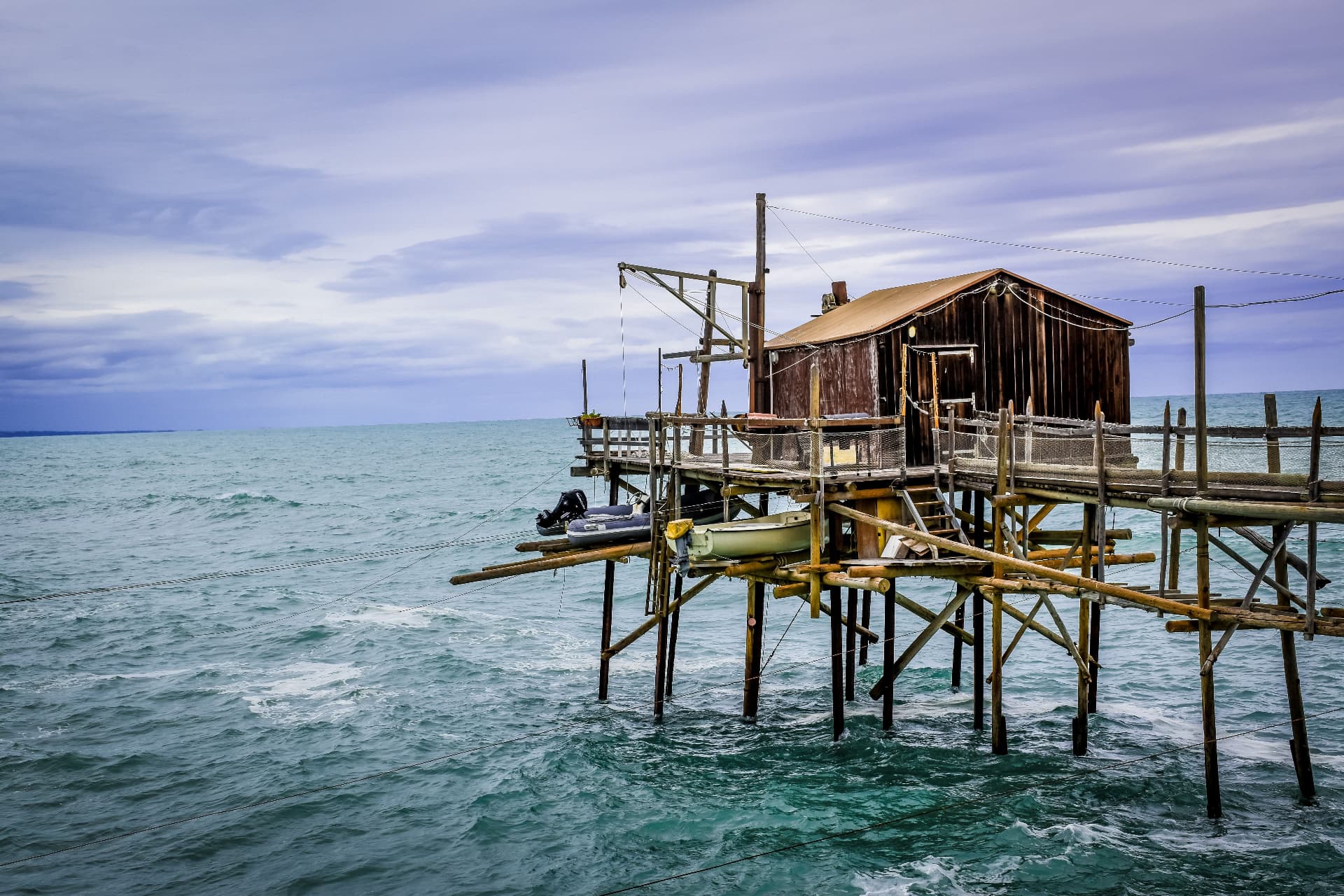 A wooden trabocco on stilts above the Adriatic, its nets and cranes against the sky
