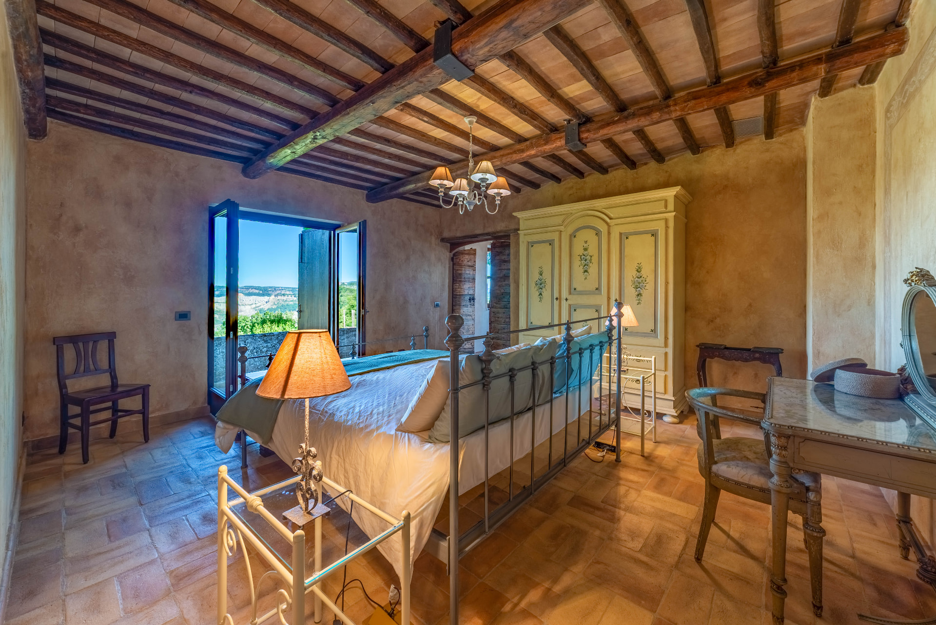 The suite: iron bed, painted armoire and French doors open onto the valley