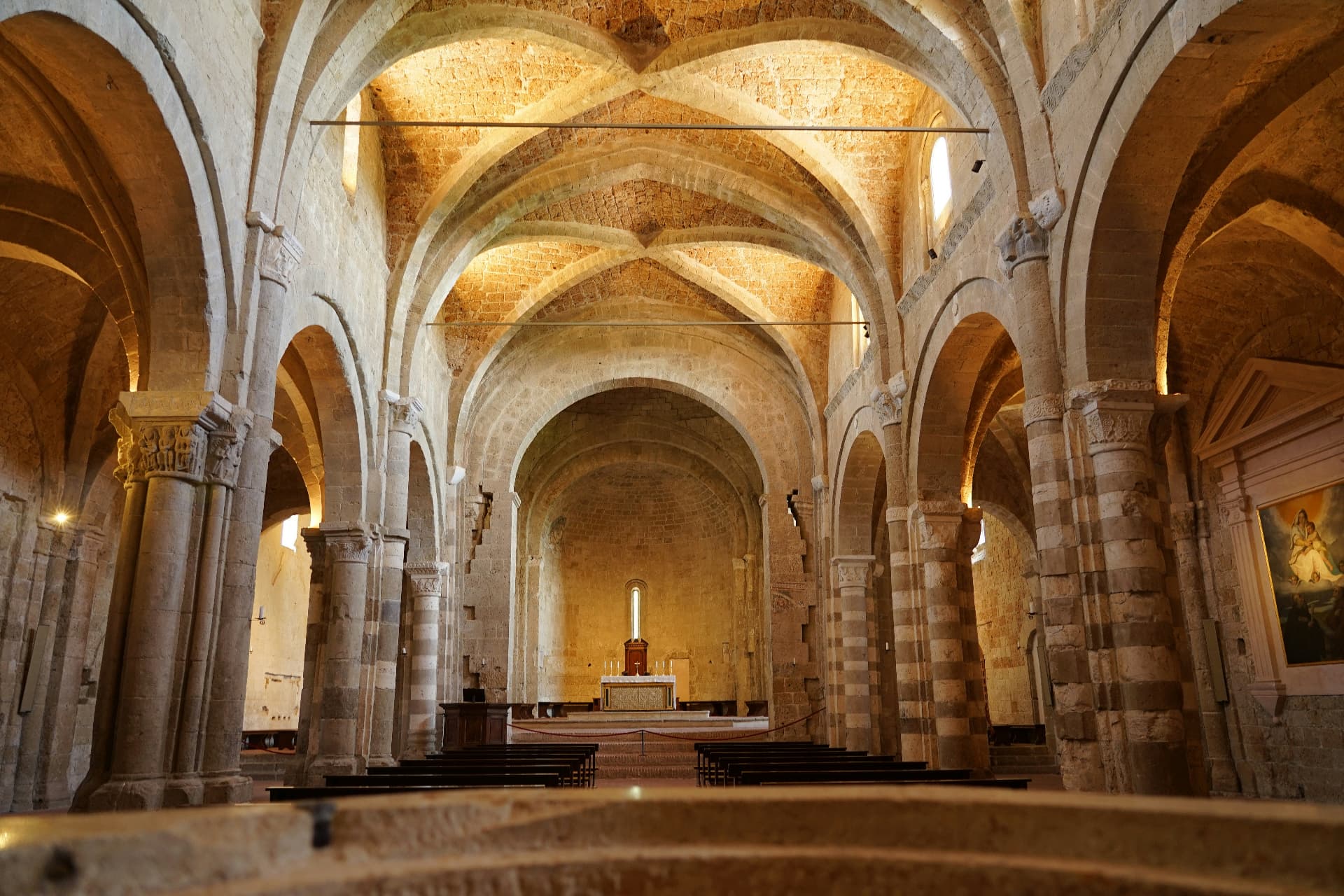 The Romanesque nave of Sovana cathedral, striped columns and warm vaults