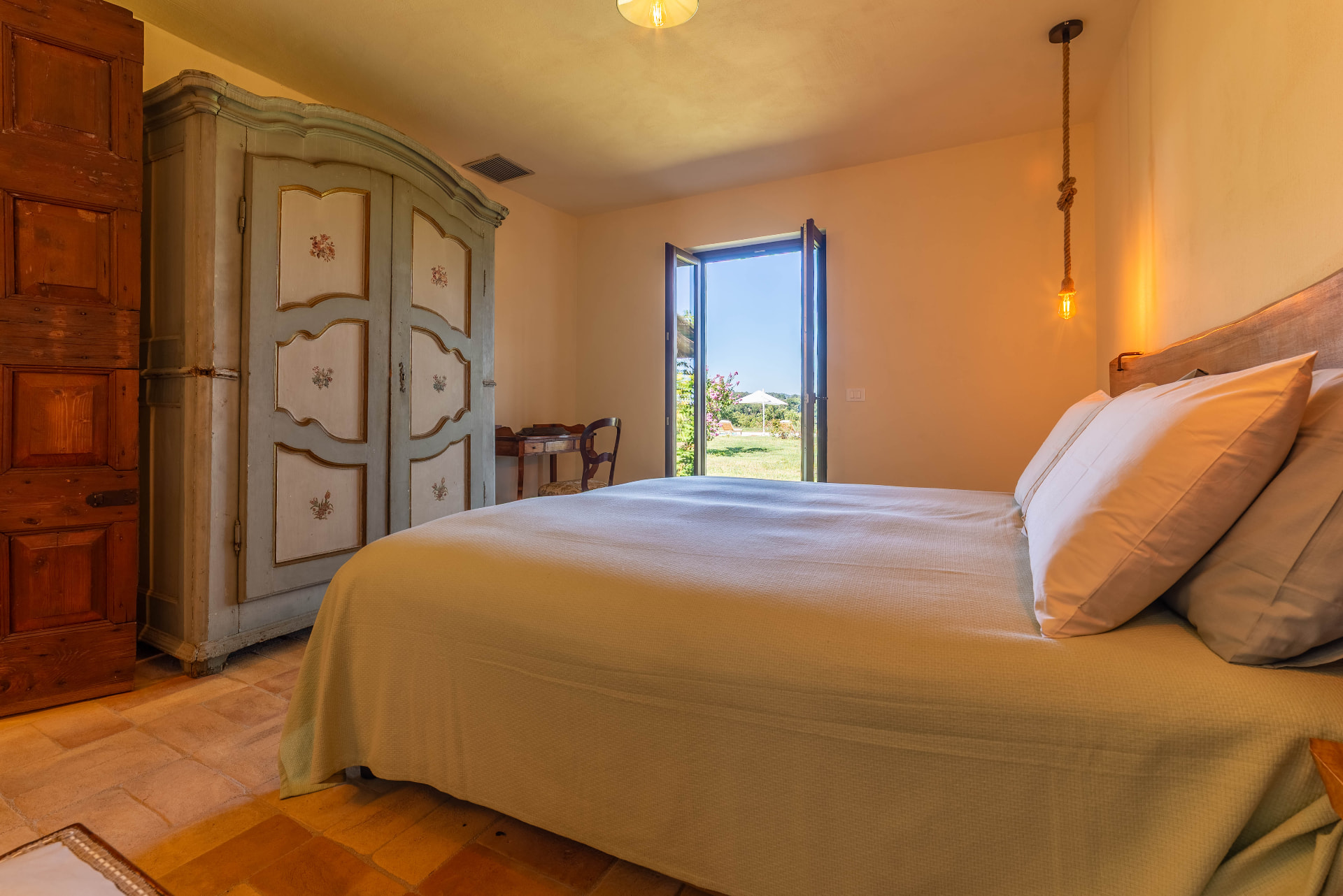 Faggio bedroom with the painted wardrobe, rope pendant lamp and French doors open onto the garden