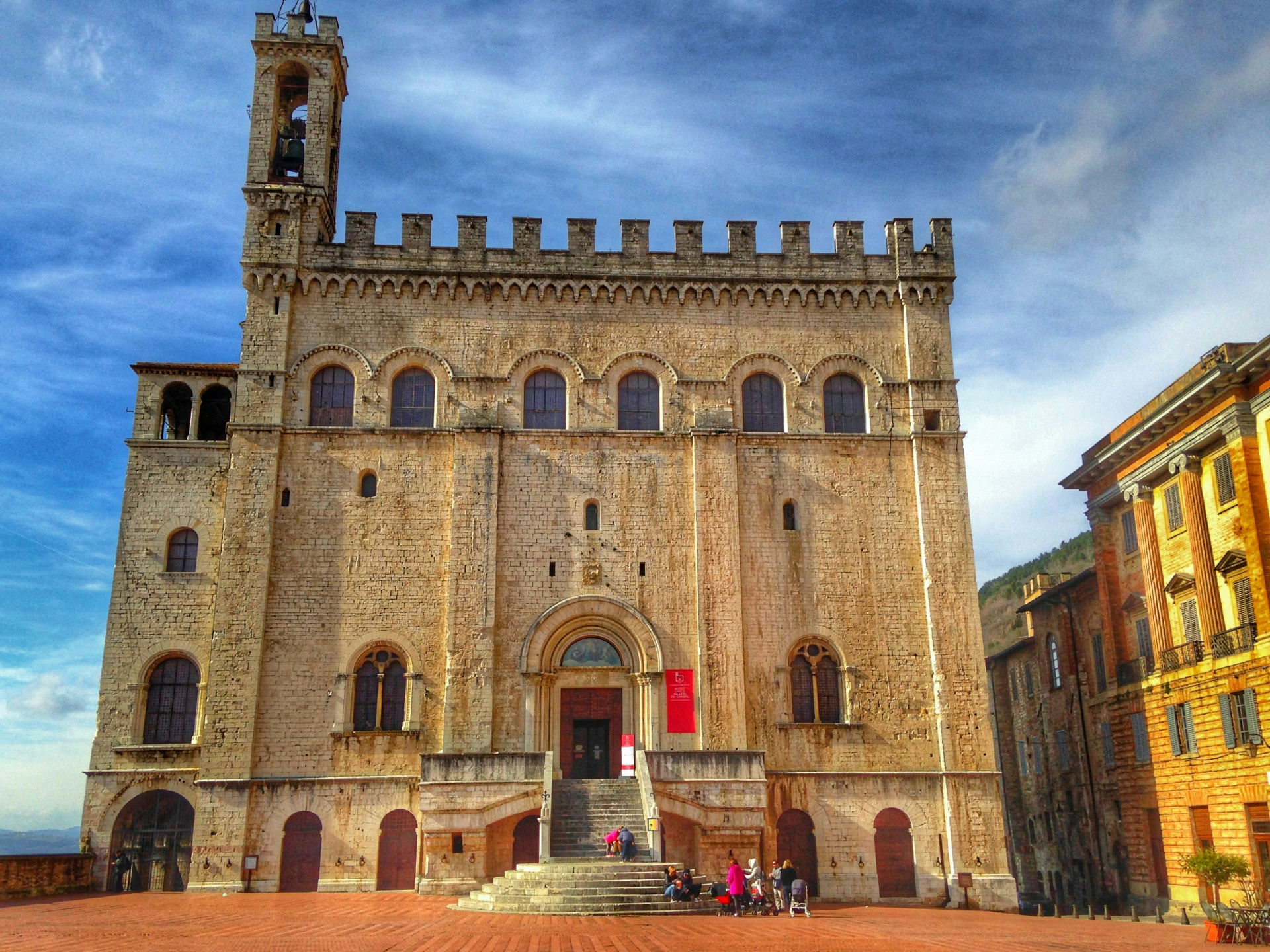 Palazzo dei Consoli above its piazza, crenellated stone and a leaning bell tower
