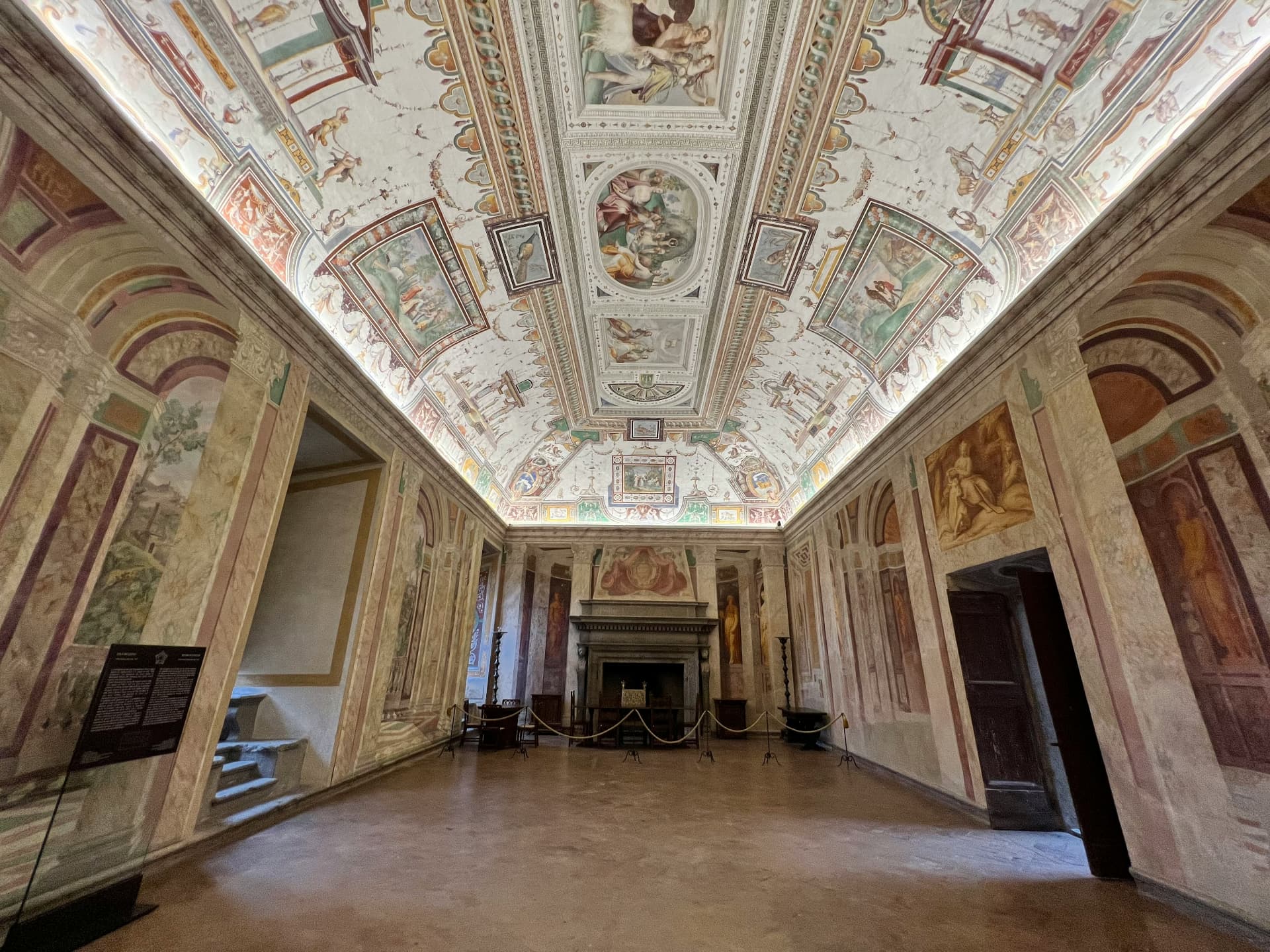 A frescoed hall in Palazzo Farnese, the vaulted ceiling running toward a stone fireplace