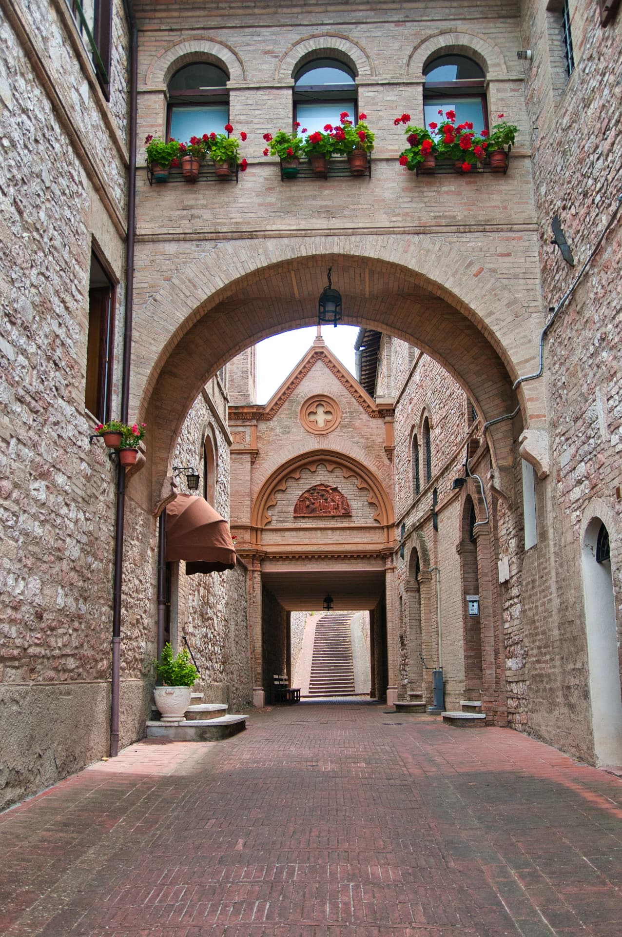 A brick arch and flower boxes above a stepped lane in Assisi
