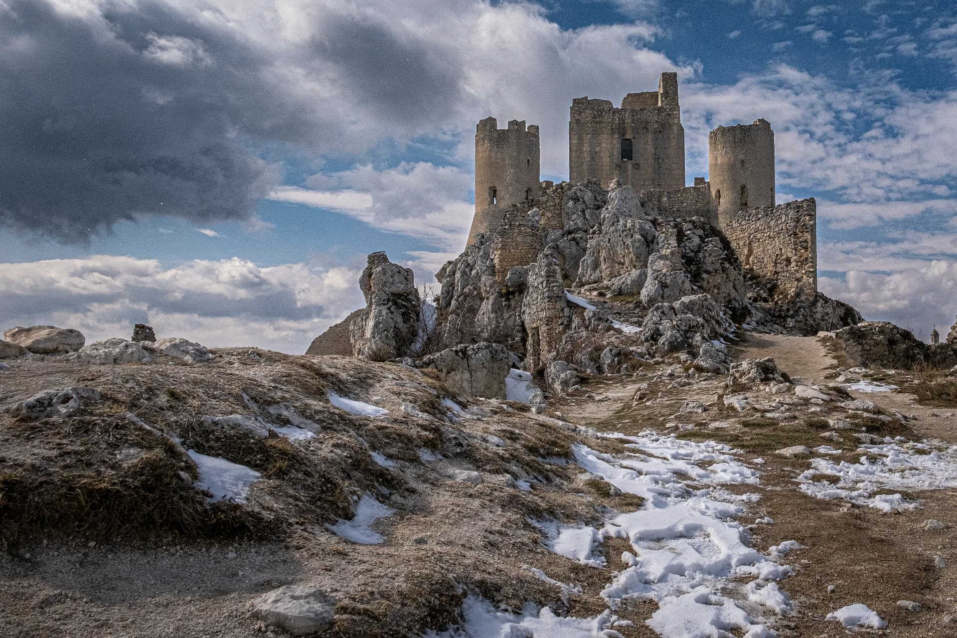 The towers of Rocca Calascio rising from the rock among patches of snow
