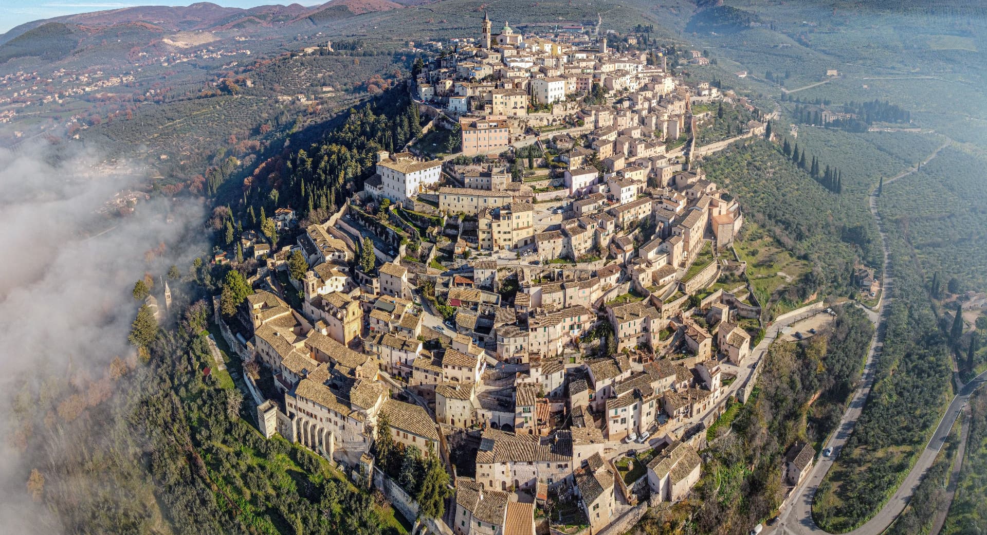 A hilltop village seen from the air above the morning mist