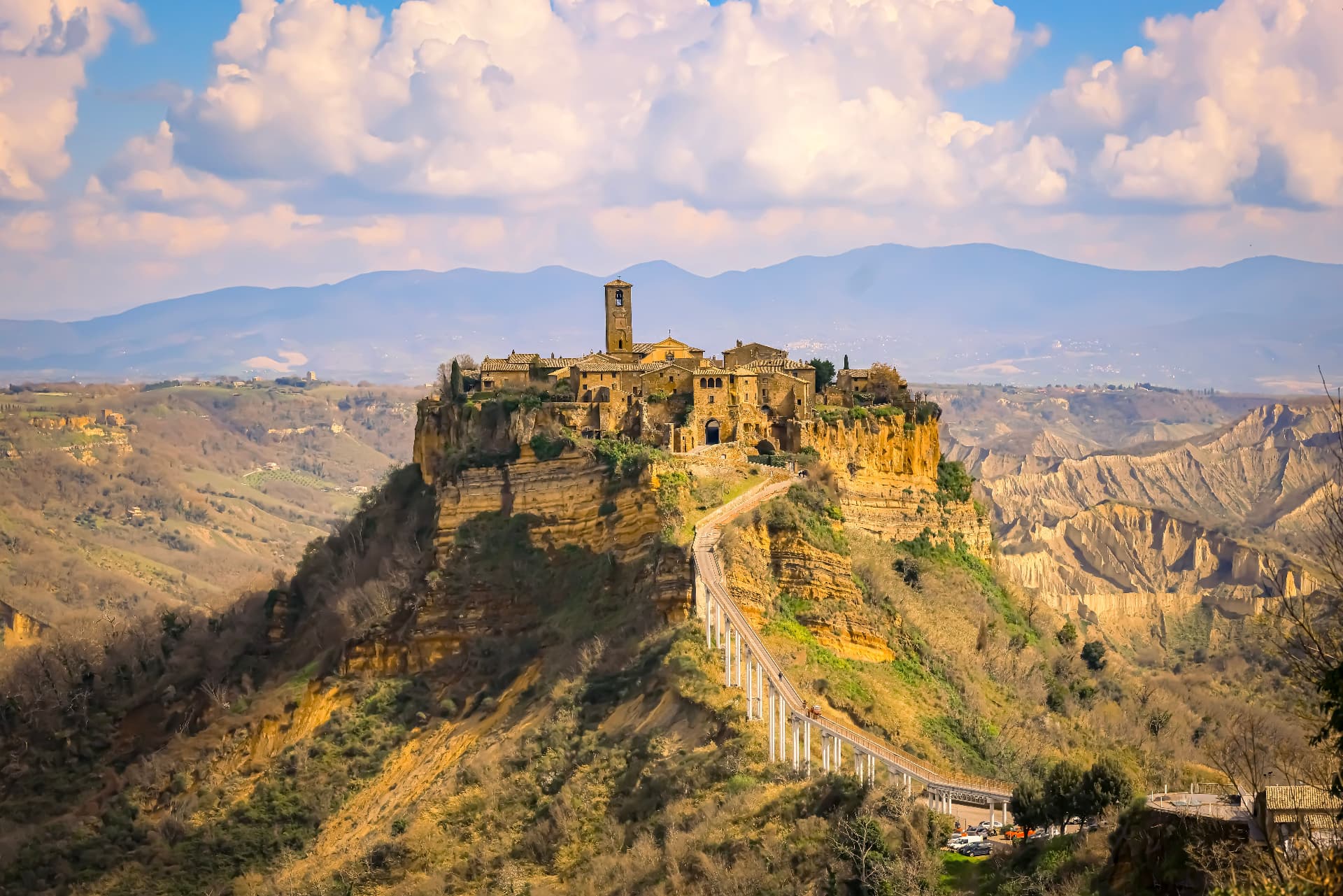Civita on its cliff and the long footbridge, seen from the valley in afternoon light