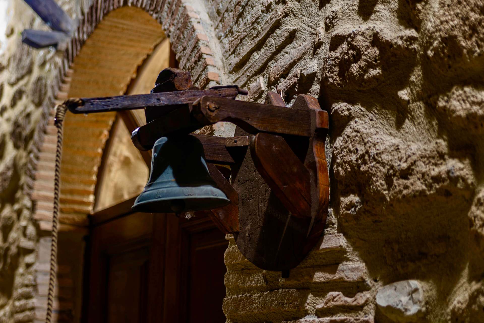 The old bell mounted beside the stone entrance