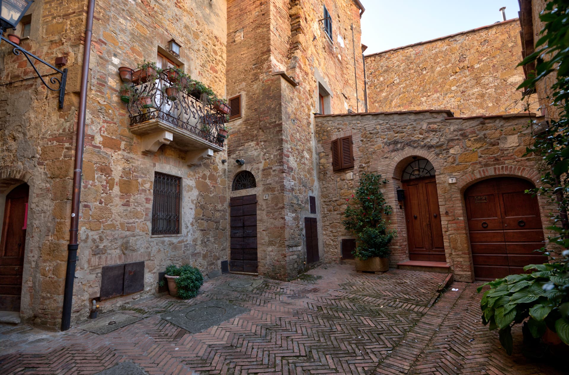 A quiet brick-paved courtyard between old stone houses at dusk