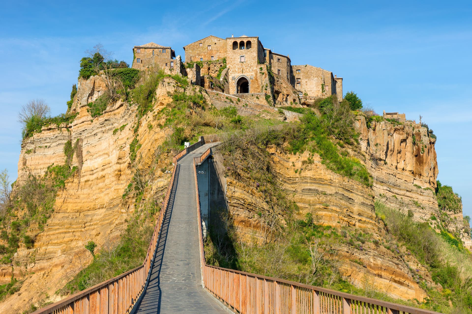 The empty footbridge climbing toward the gate of Civita, the eroded tufa cliff rising on either side