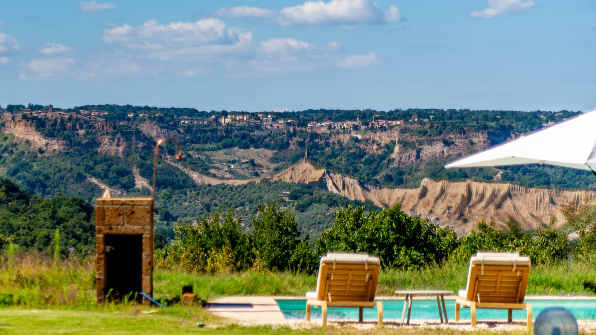 The pool with wooden loungers, overlooking the calanche and the village across the valley